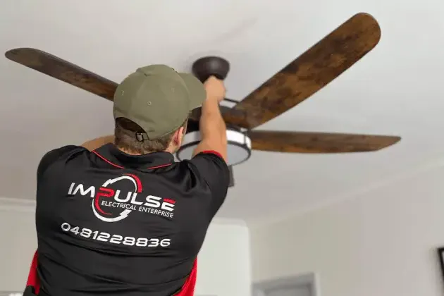 Impulse Electrical Enterprise electrician installing a timber-blade ceiling fan