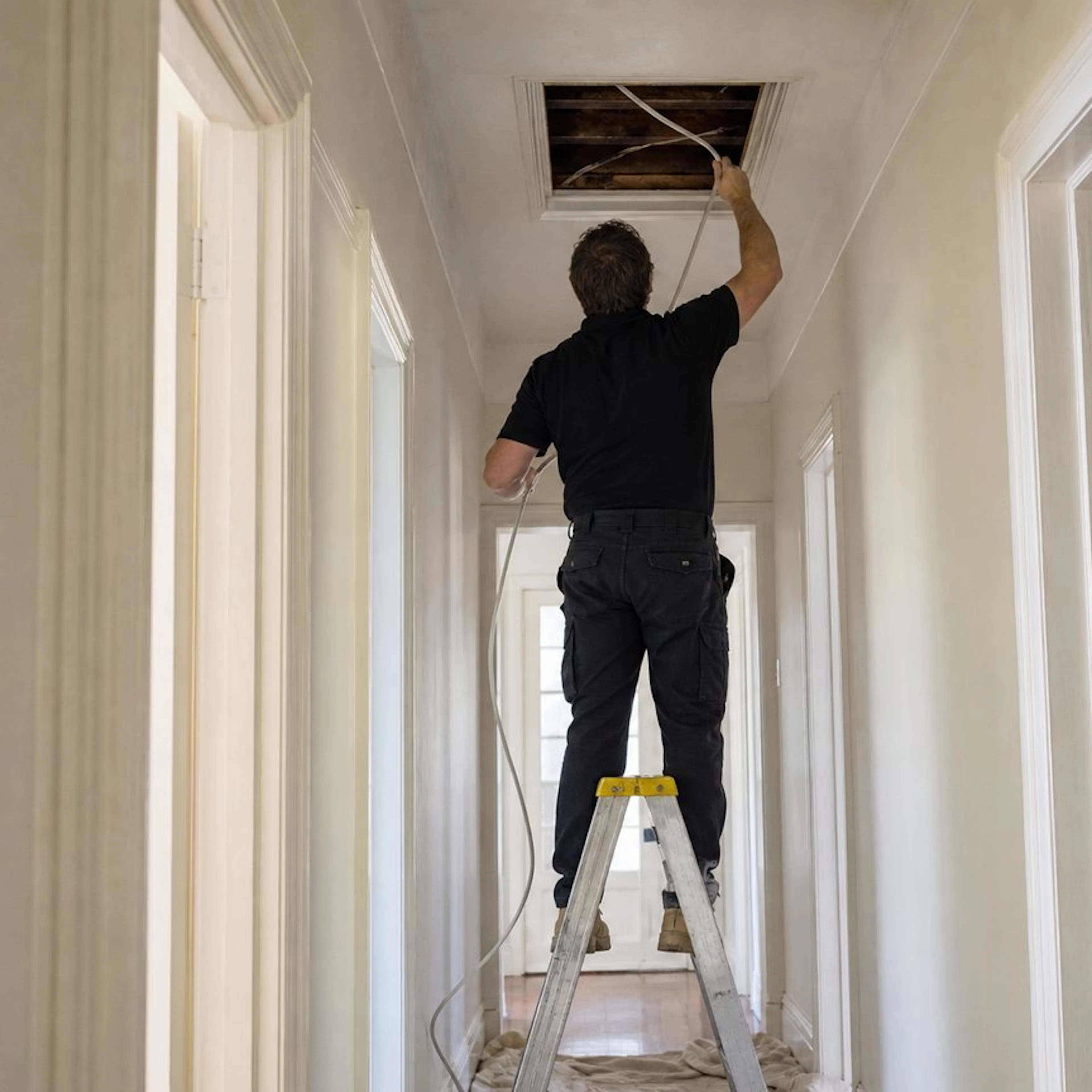 Electrician running new cable through a ceiling for a rewire
