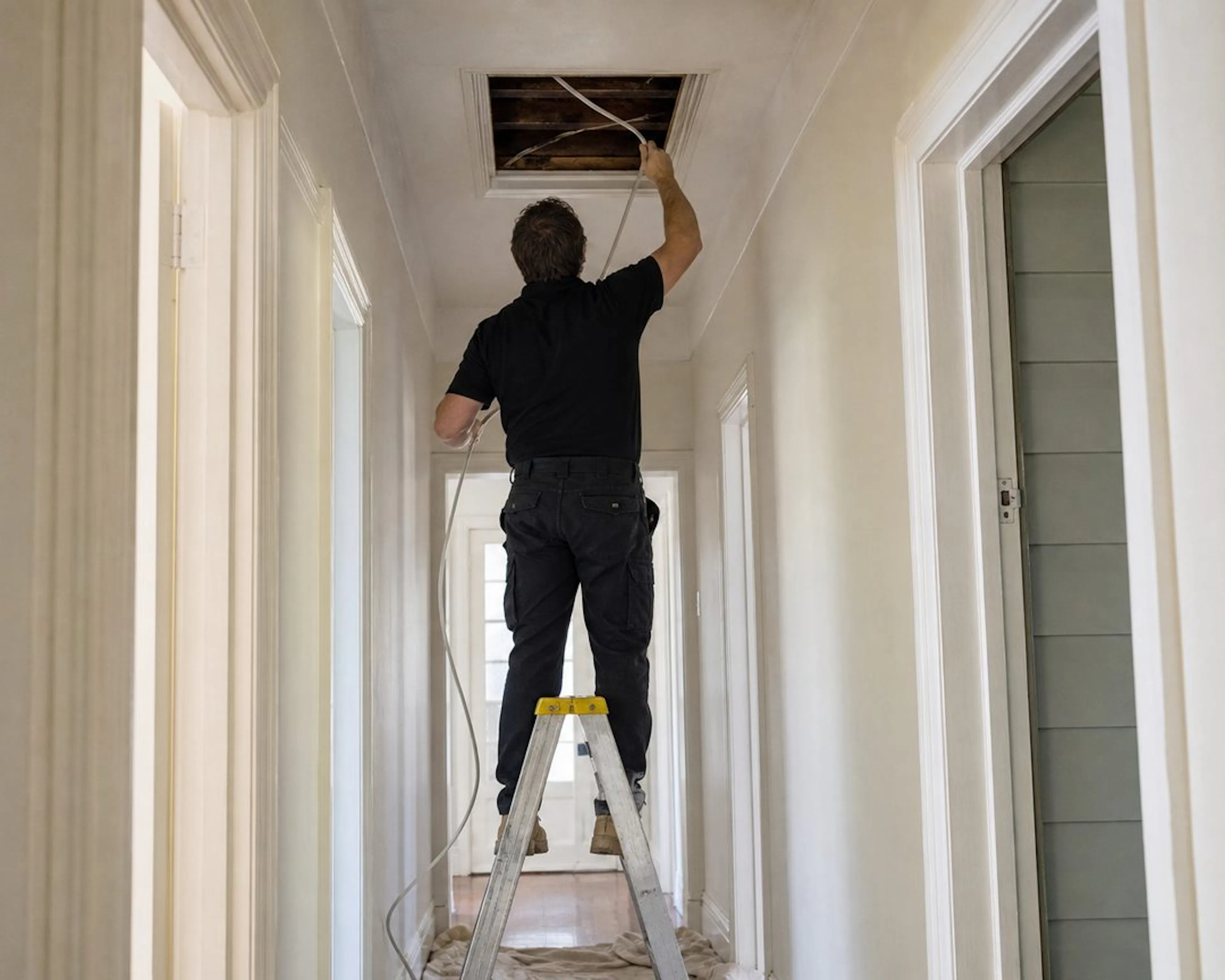 Electrician running new cable through a ceiling for a rewire