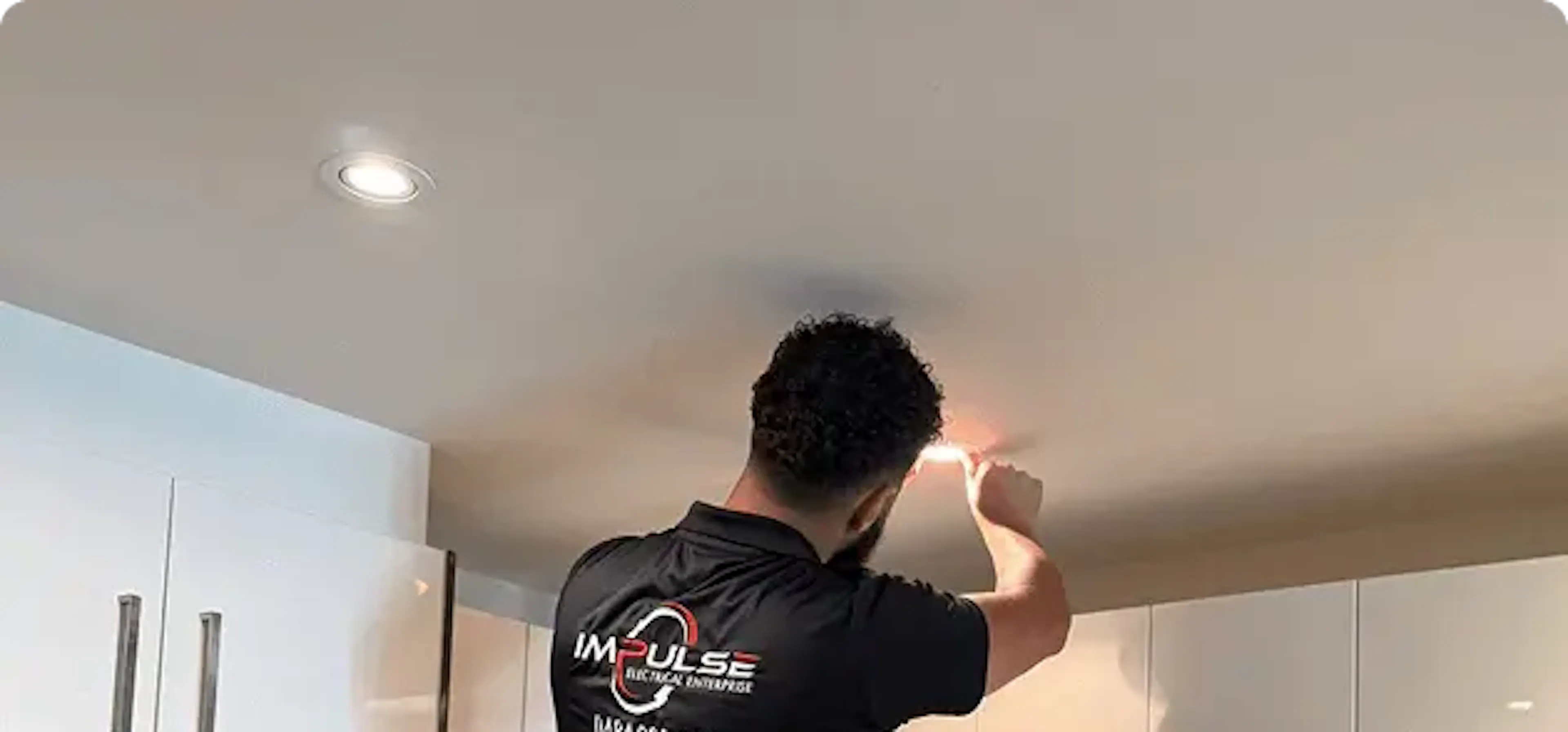 Electrician fitting a ceiling light in a kitchen