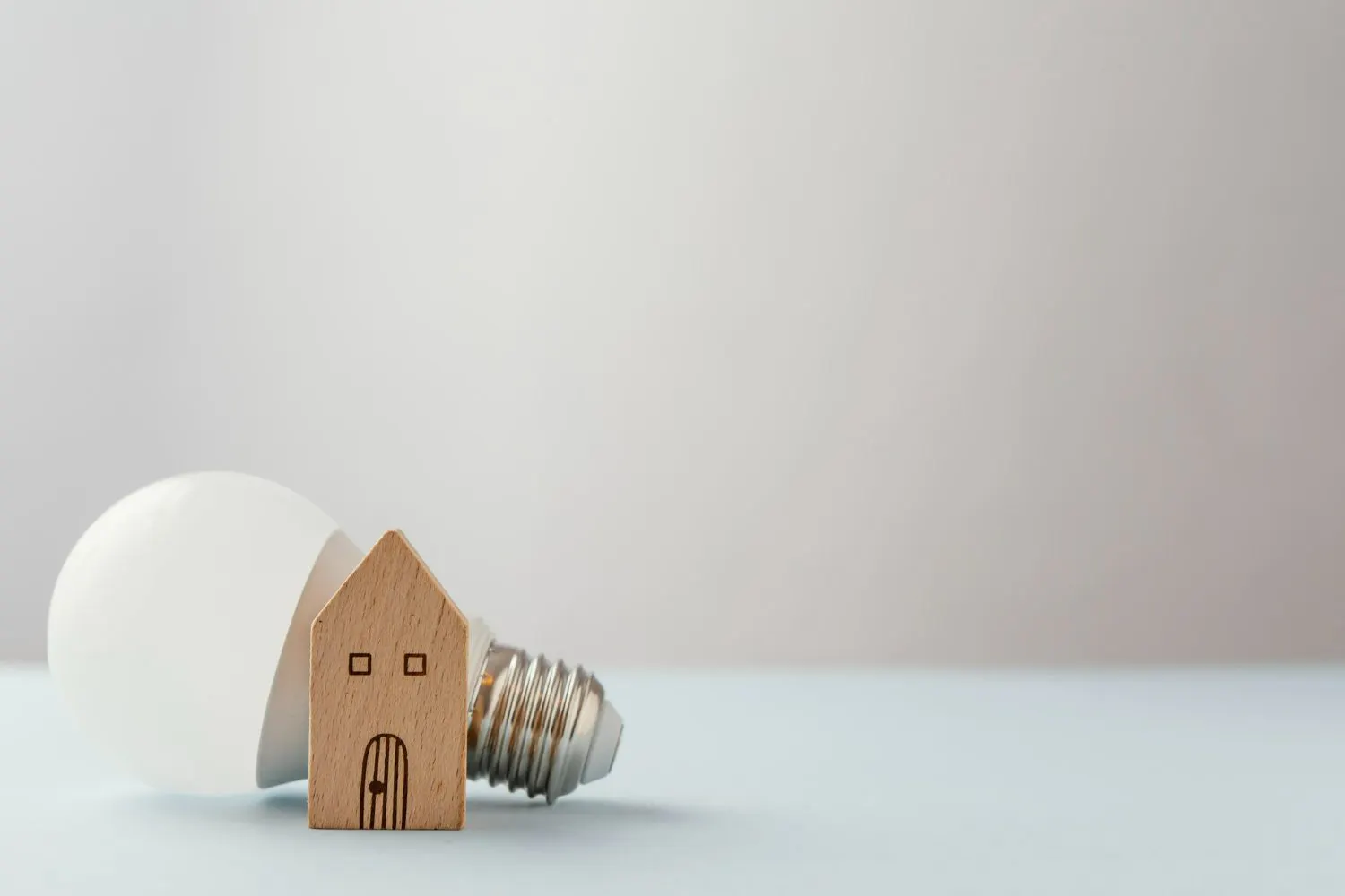 Light bulb beside a small wooden model house