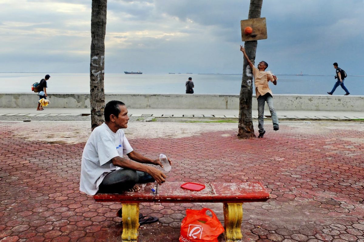 A man cools off with a drink and sea breeze in Baywalk, Manila Bay, Philippines. 