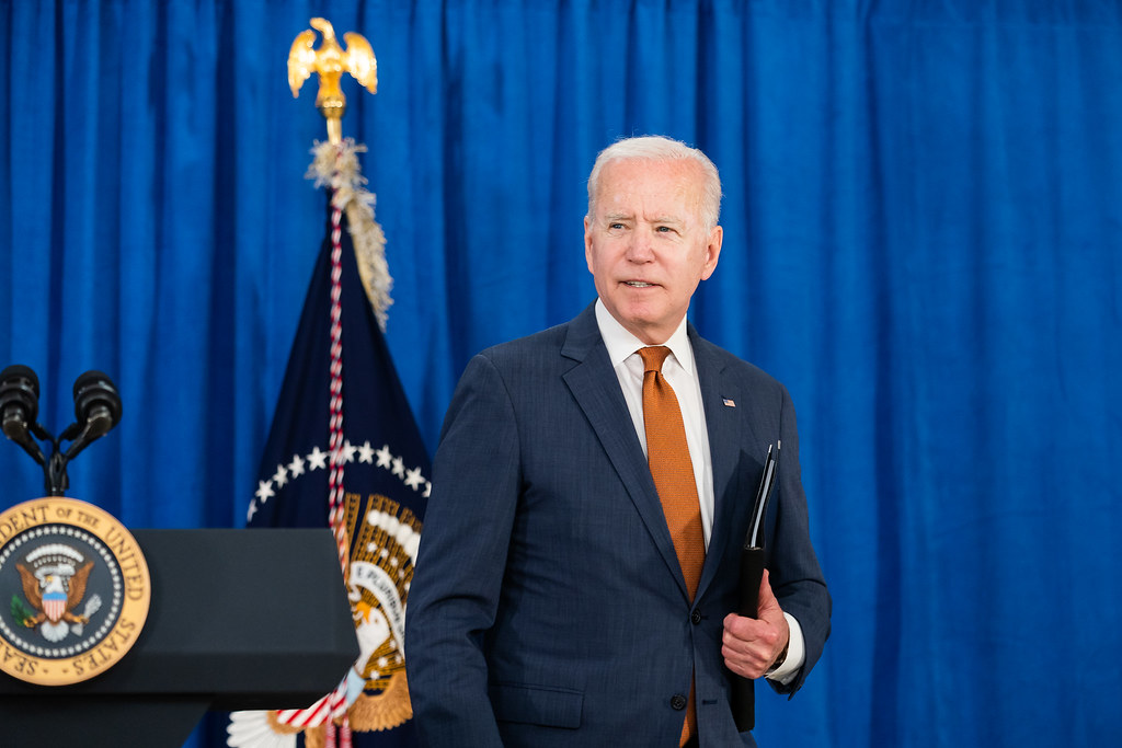 President Biden walking away from podium holding a binder.
