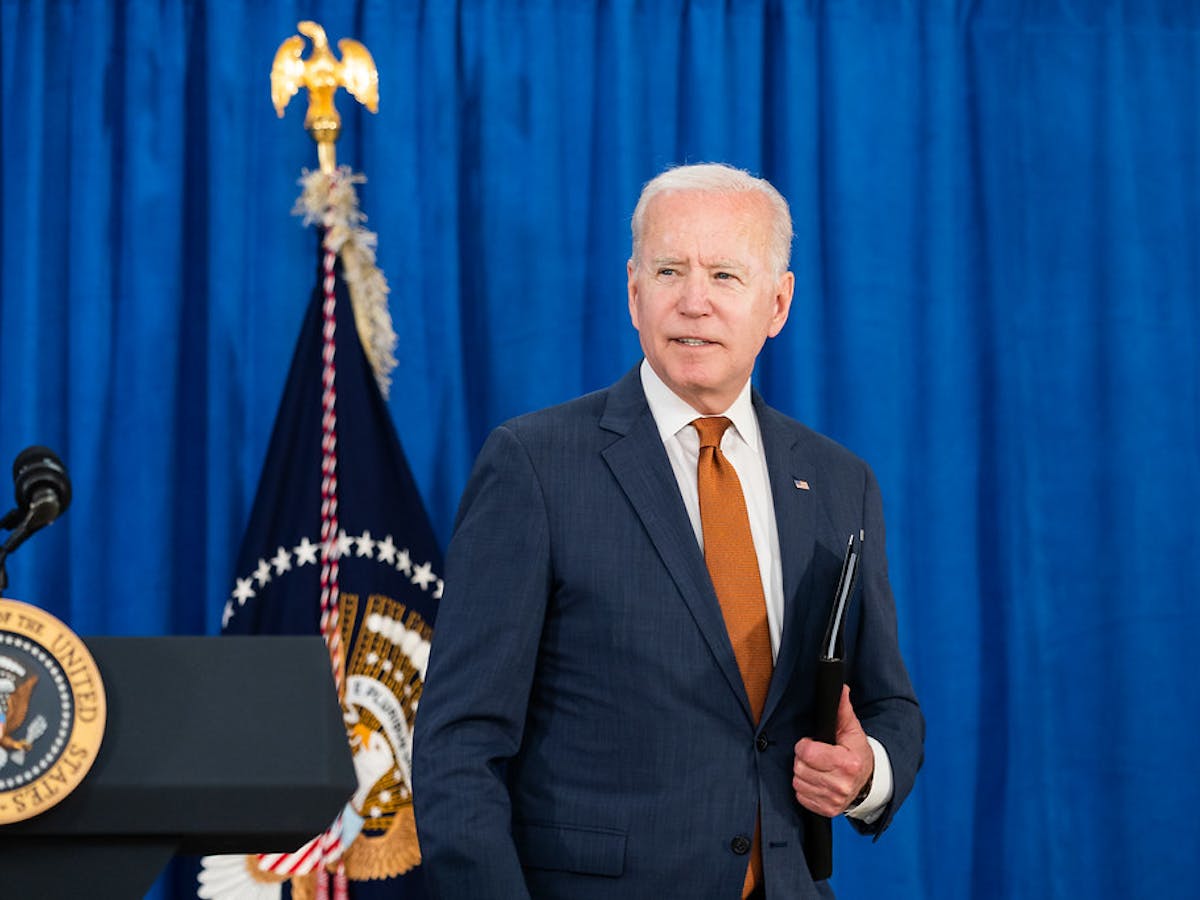 President Biden walking away from podium holding a binder.