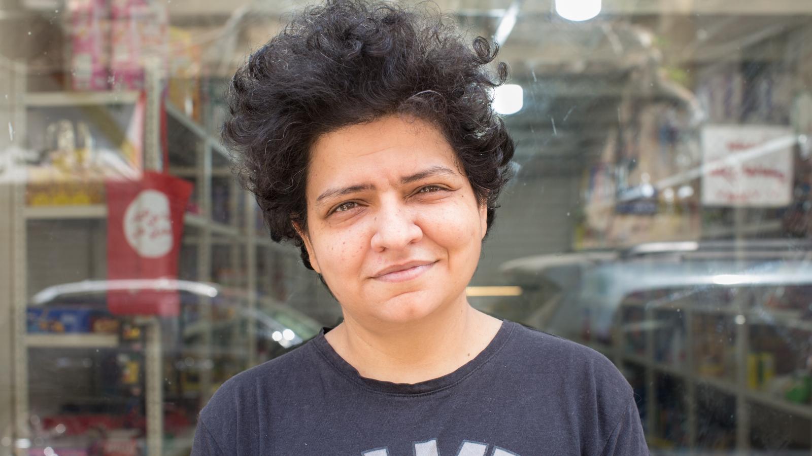 Nadine Moawad stands in front of shop window of Dikkeneh Consumer Cooperative grocery store. 