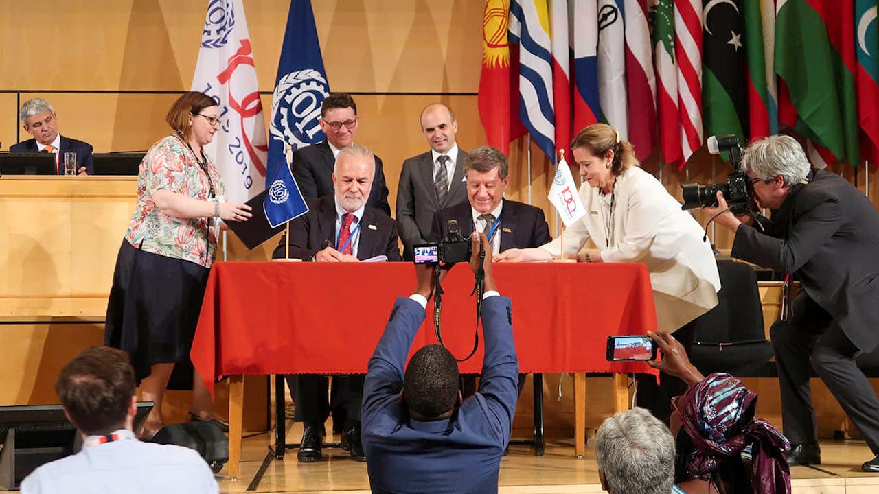 The ILO Director-General and the Chairman on the 2019 ILC on a stage, signing the ILO Centenary Declaration on the Future of Work at the International Labour Conference in Geneva on June 2019.
