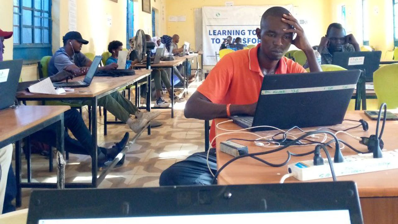Young people look at laptop screens in the internet centre in Kakuma refugee camp in Kenya.