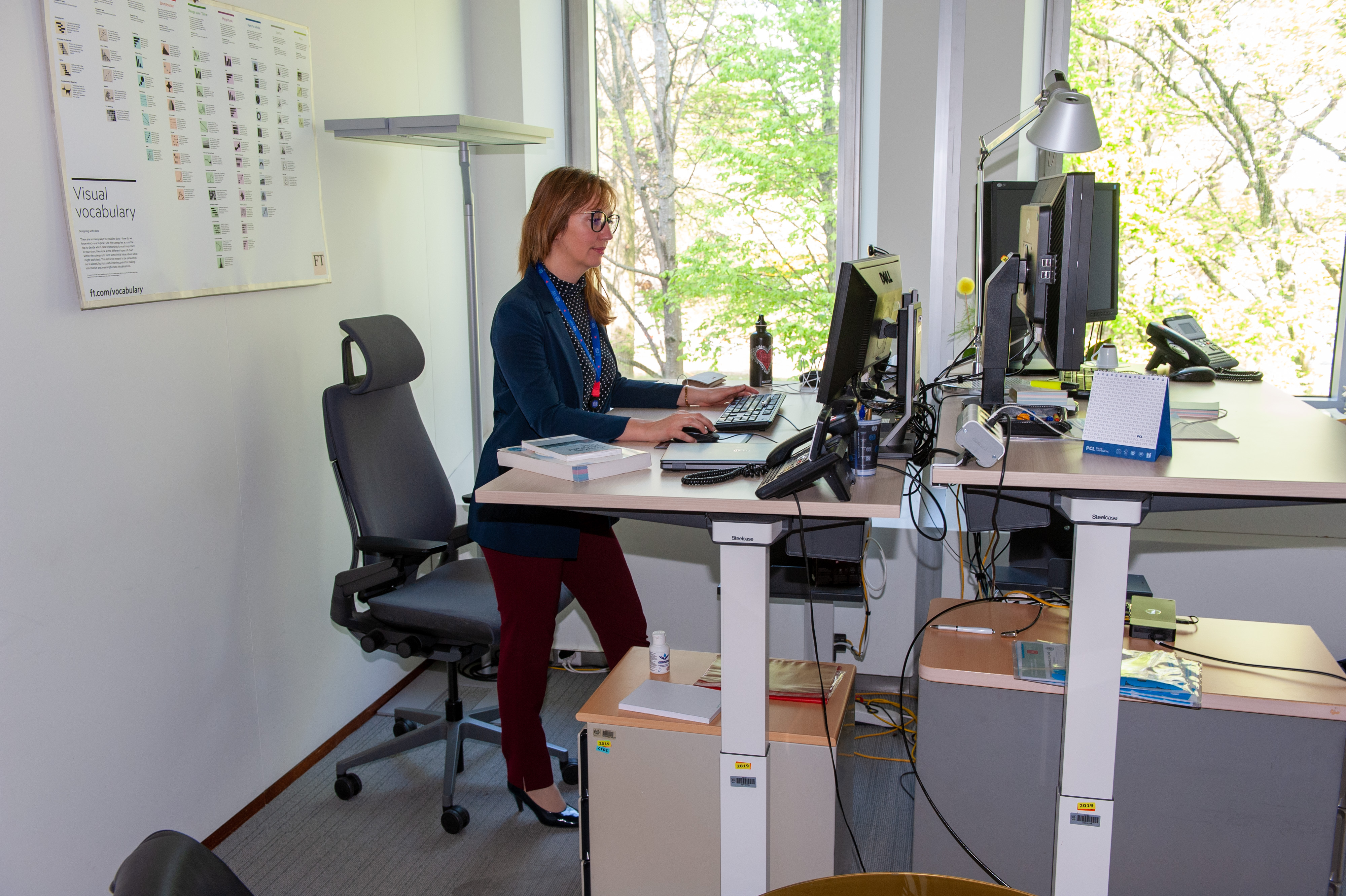 Raya Ubenova stands in front of a desk and works at a computer. 