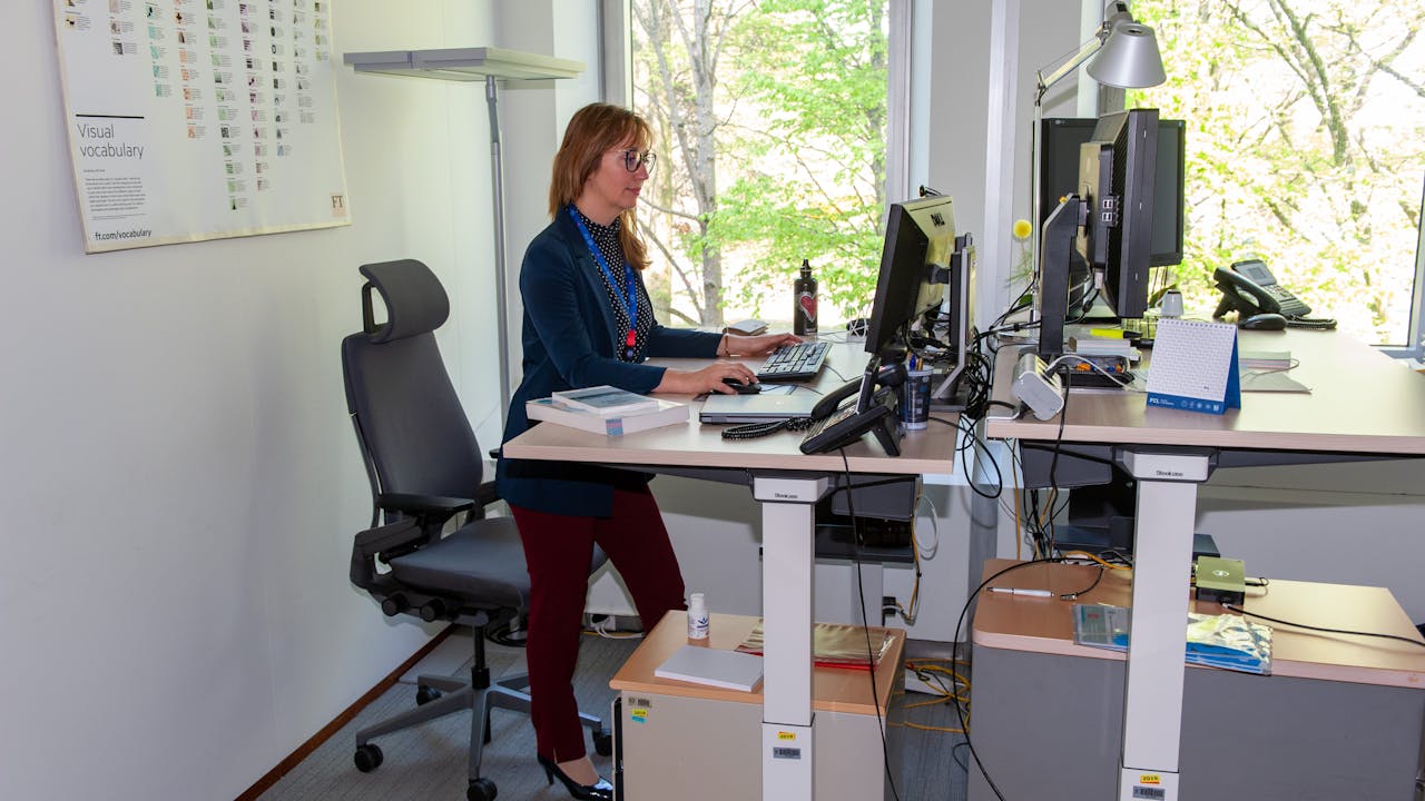 Raya Ubenova se tient devant un bureau et travaille sur un ordinateur.