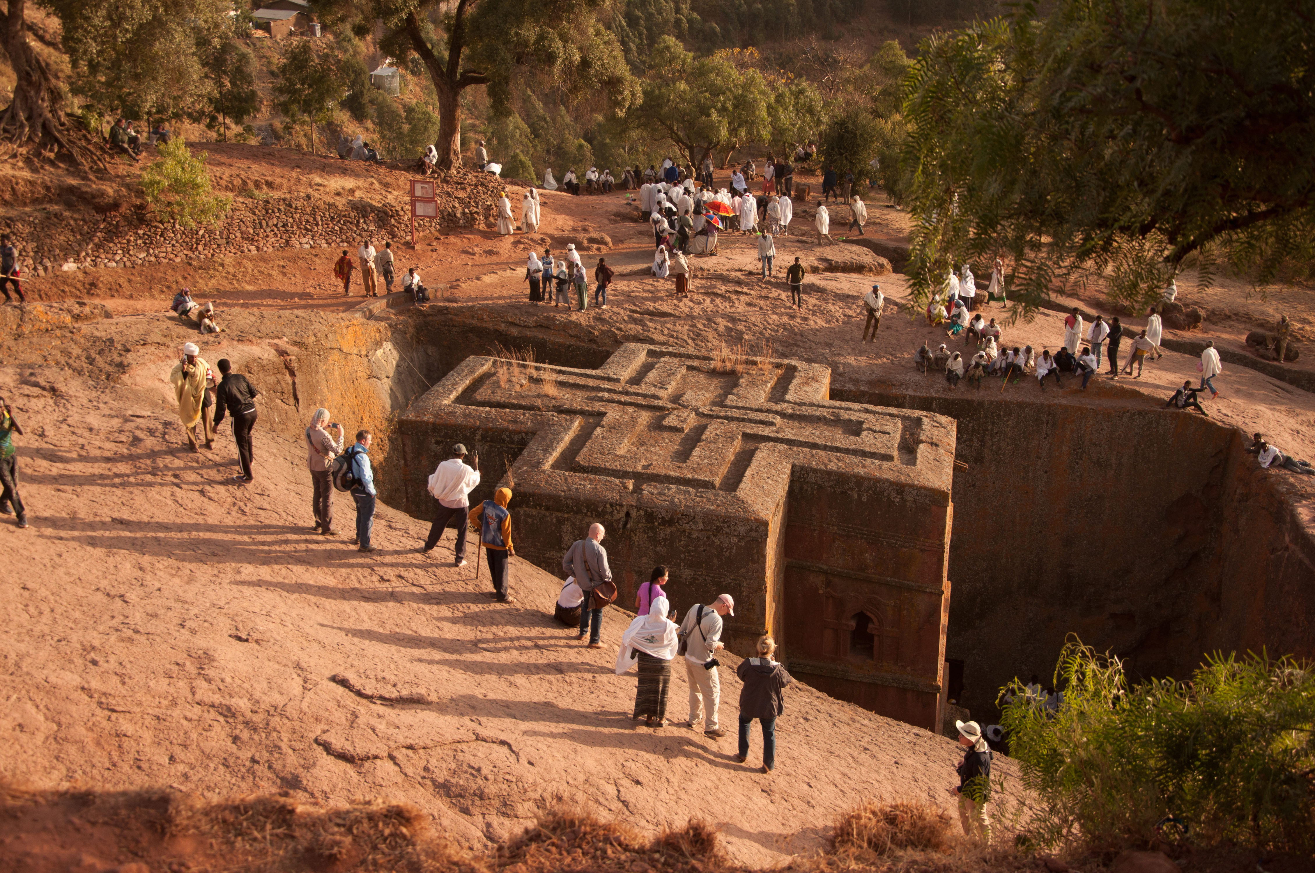 Christian pilgrims in traditional clothes and tourists gather to celebrate Orthodox Christmas Eve in front of famous rock hewn church of Bet Giyorgis in Lalibela, Ethiopia. It is carved from solid rock in the shape of a cross.
