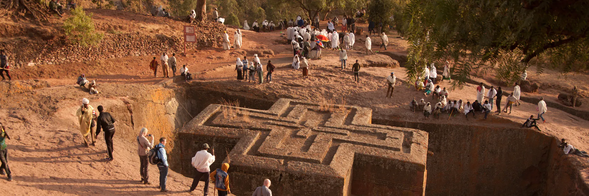 Christian pilgrims in traditional clothes and tourists gather to celebrate Orthodox Christmas Eve in front of famous rock hewn church of Bet Giyorgis in Lalibela, Ethiopia. It is carved from solid rock in the shape of a cross.