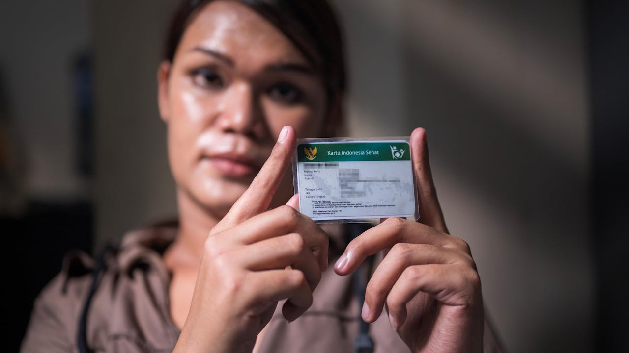 A trans woman holds up her national health insurance card.