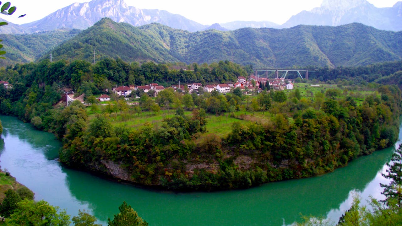 The town of Jasablanca with the Neretva river in the foreground and mountains in the background.
