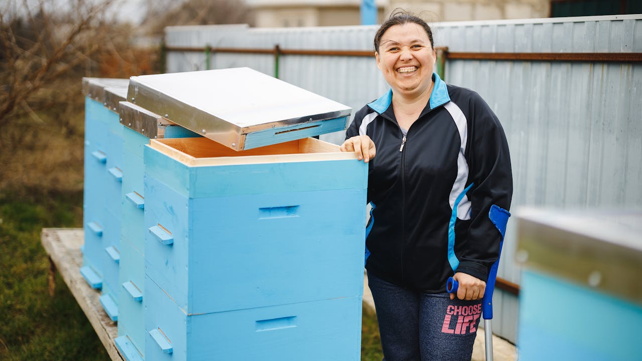 Viorica stands with the help of a crutch next to her beehives.