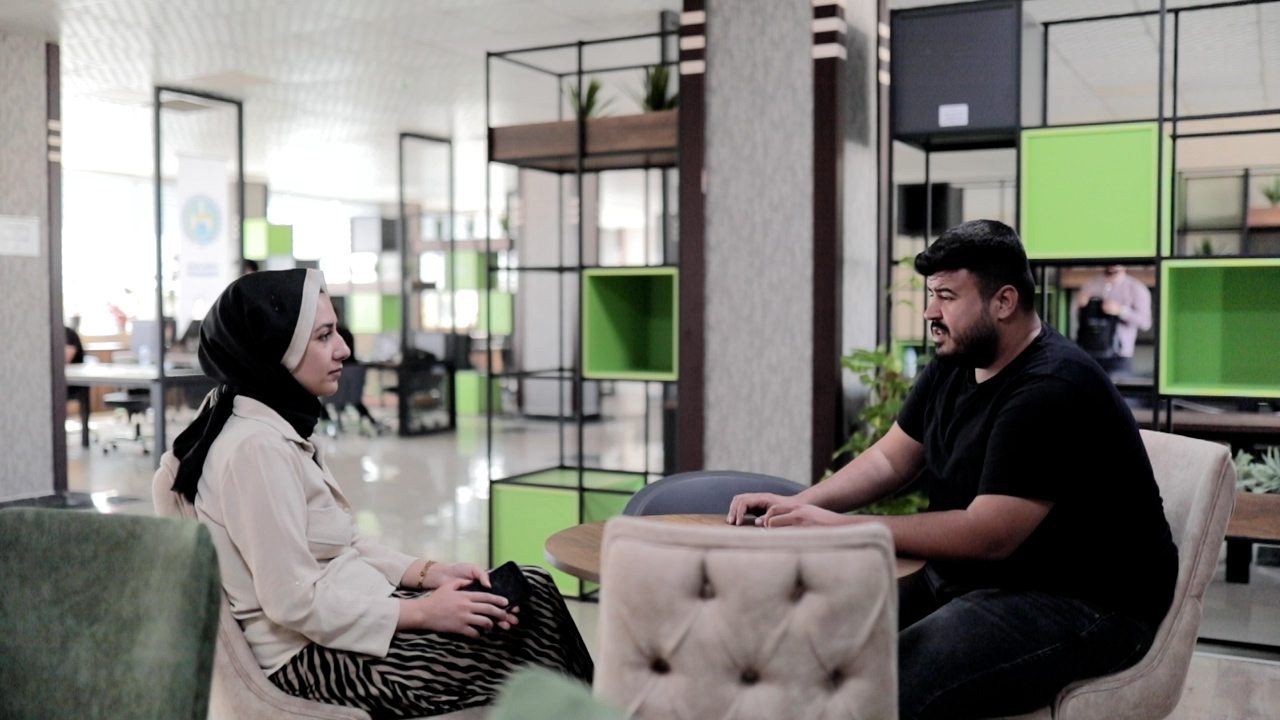A therapy session takes place. The client, seated on the right is a man. The therapist, seated on the left, is a woman. 
