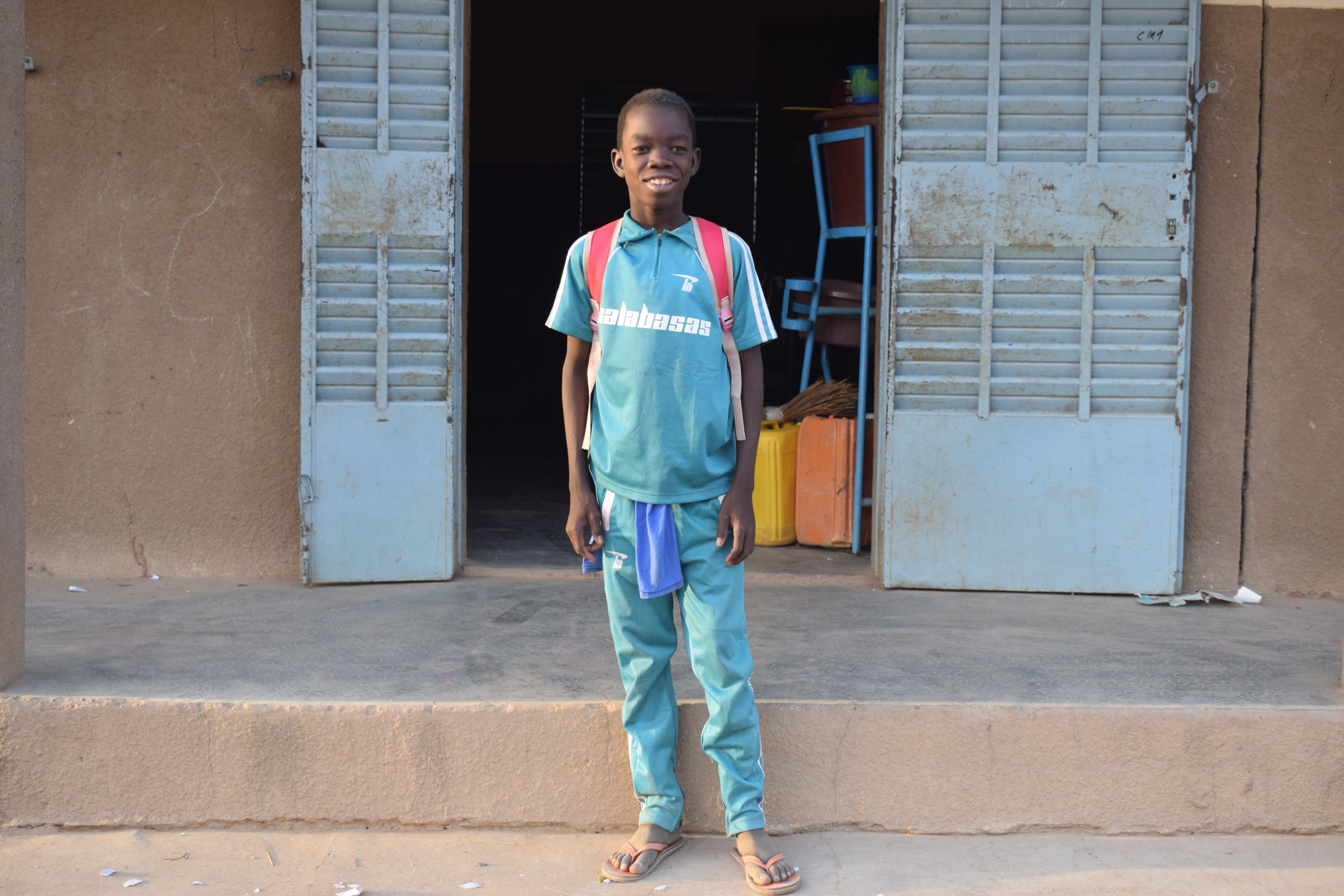 Domboué Nibéissé se tient devant l'entrée de l'école.