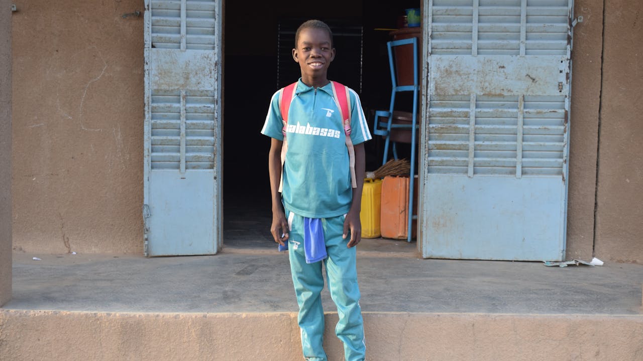Domboué Nibéissé se tient devant l'entrée de l'école.