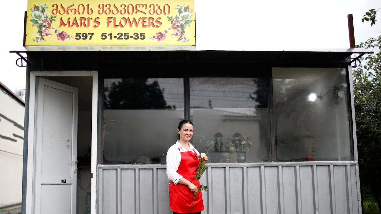 Mariam Kobalia se tient devant son magasin de fleurs « Les fleurs de Mari » et tient un bouquet de roses.