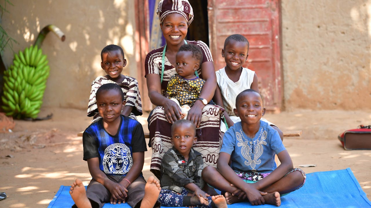 Angelique Kahindo sentada con sus seis hijos. Todos sonríen a la cámara. 