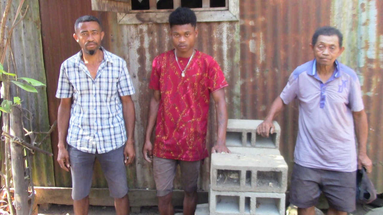 Sergio, his uncle and his grandfather stand next to the cinder blocks made by Sergio.