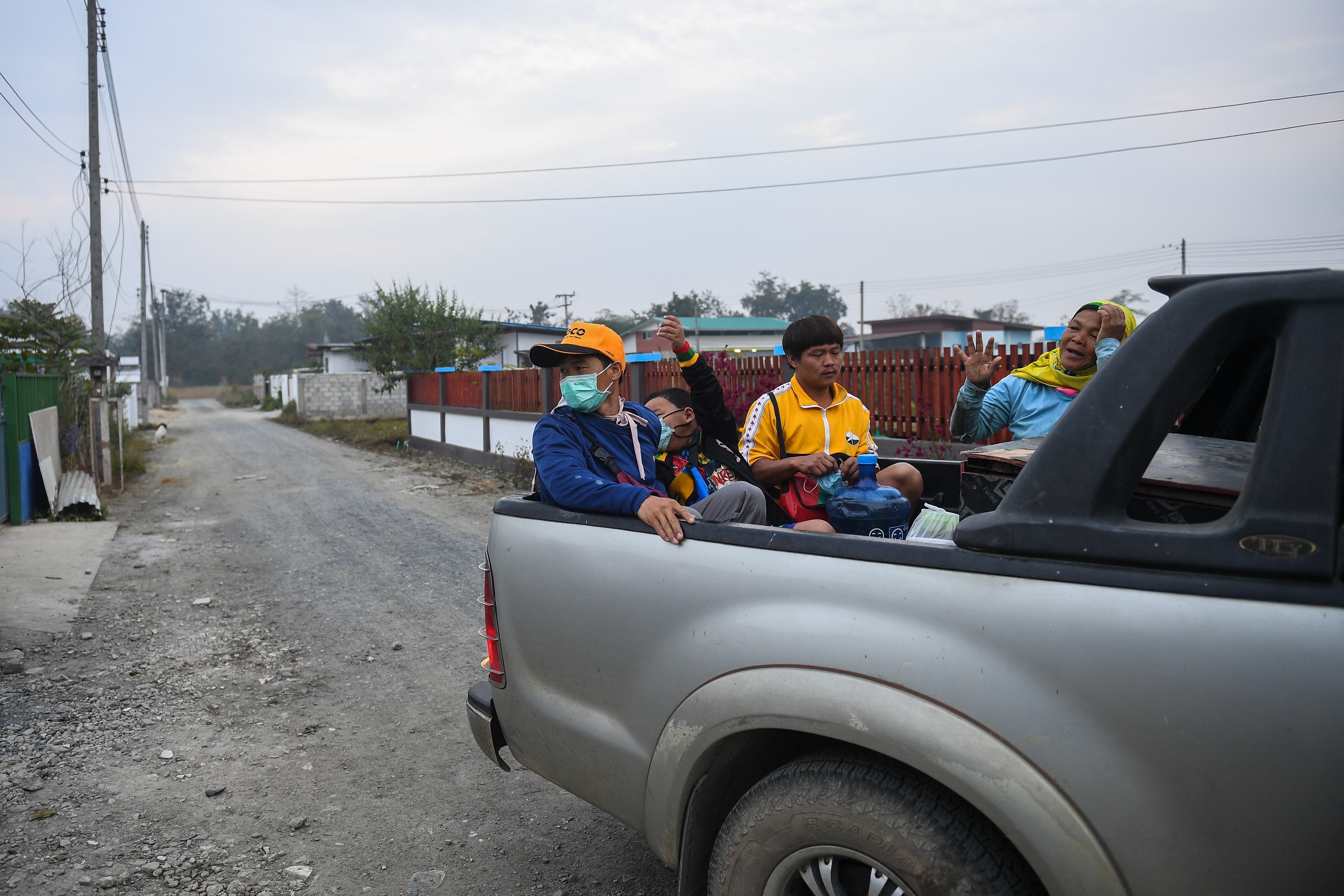 Sai Sai and others sit in the back of a pick-up truck.