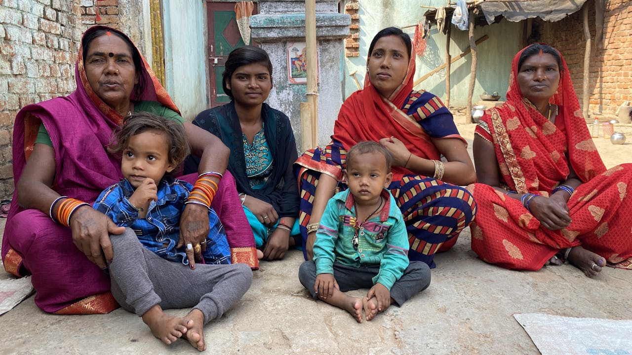 Suman Kumari est assise dehors, avec d’autres membres de sa famille, dont trois femmes et deux enfants en bas âge.