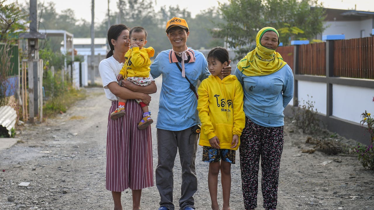 Sai Sai se tient sur la route avec sa femme, sa mère et ses deux enfants. Il affiche un large sourire.