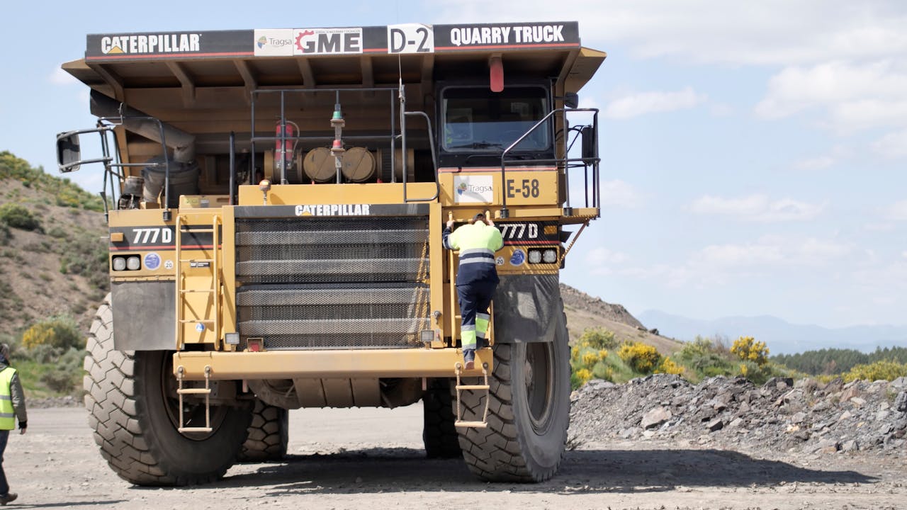 Cristina Carro climbs the ladder at the front of a quarry truck to access the driver’s seat.