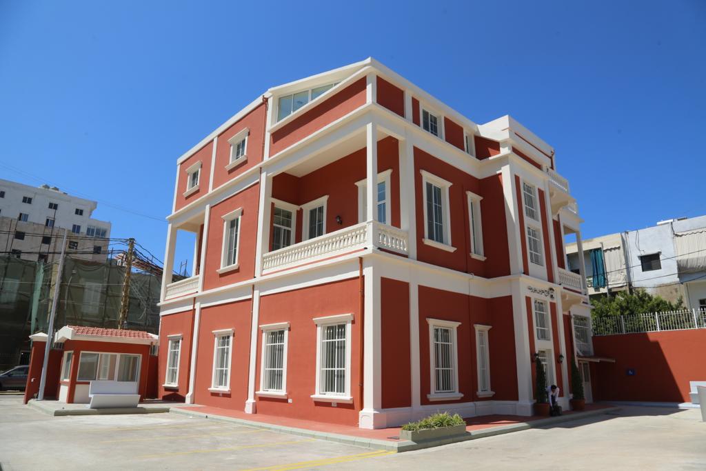 El exterior de la comisaría municipal tras las obras de rehabilitación. La pintura del edificio ha cambiado a un intenso color rojo ladrillo con ribetes blancos.