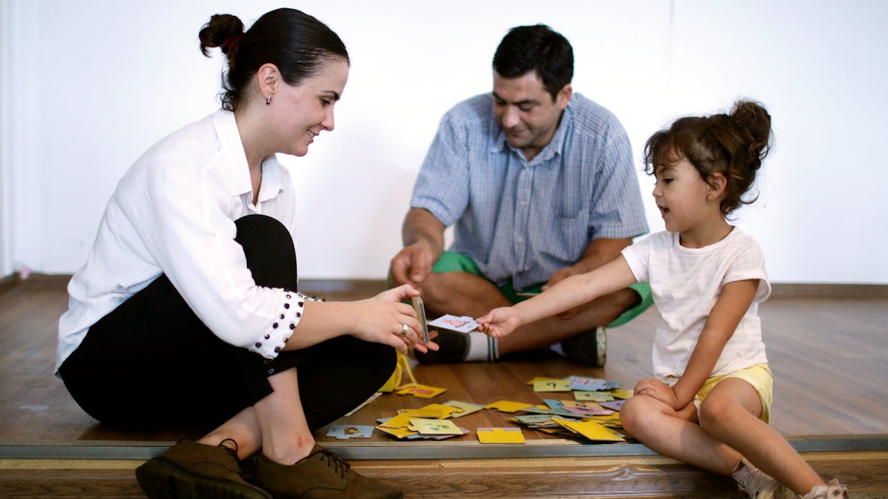 Mariam Kobalia plays a card game with her four-year-old daughter and her husband.
