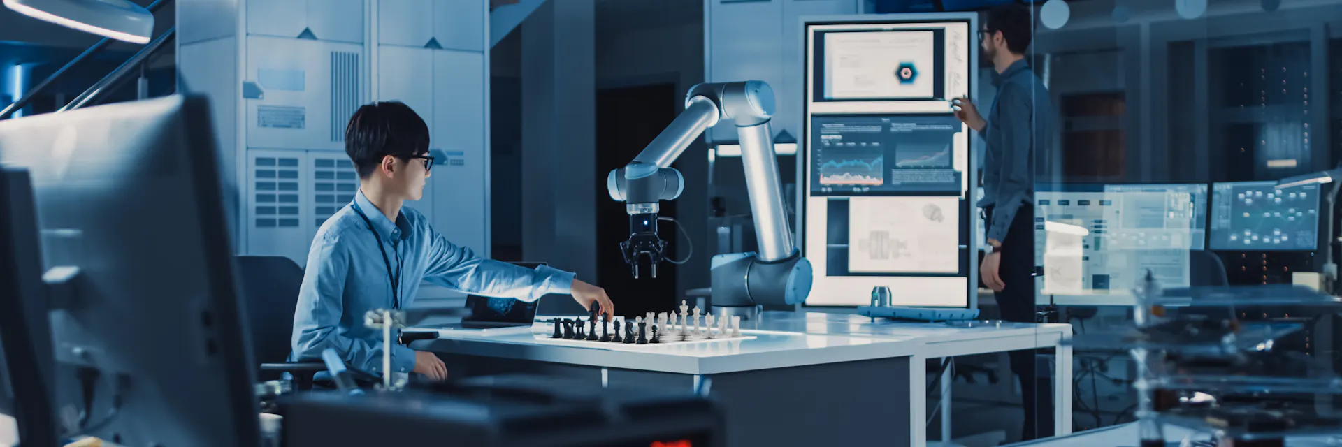 Professional Japanese Development Engineer is Testing an Artificial Intelligence Interface by Playing Chess with a Futuristic Robotic Arm. They are in a High Tech Modern Research Laboratory.