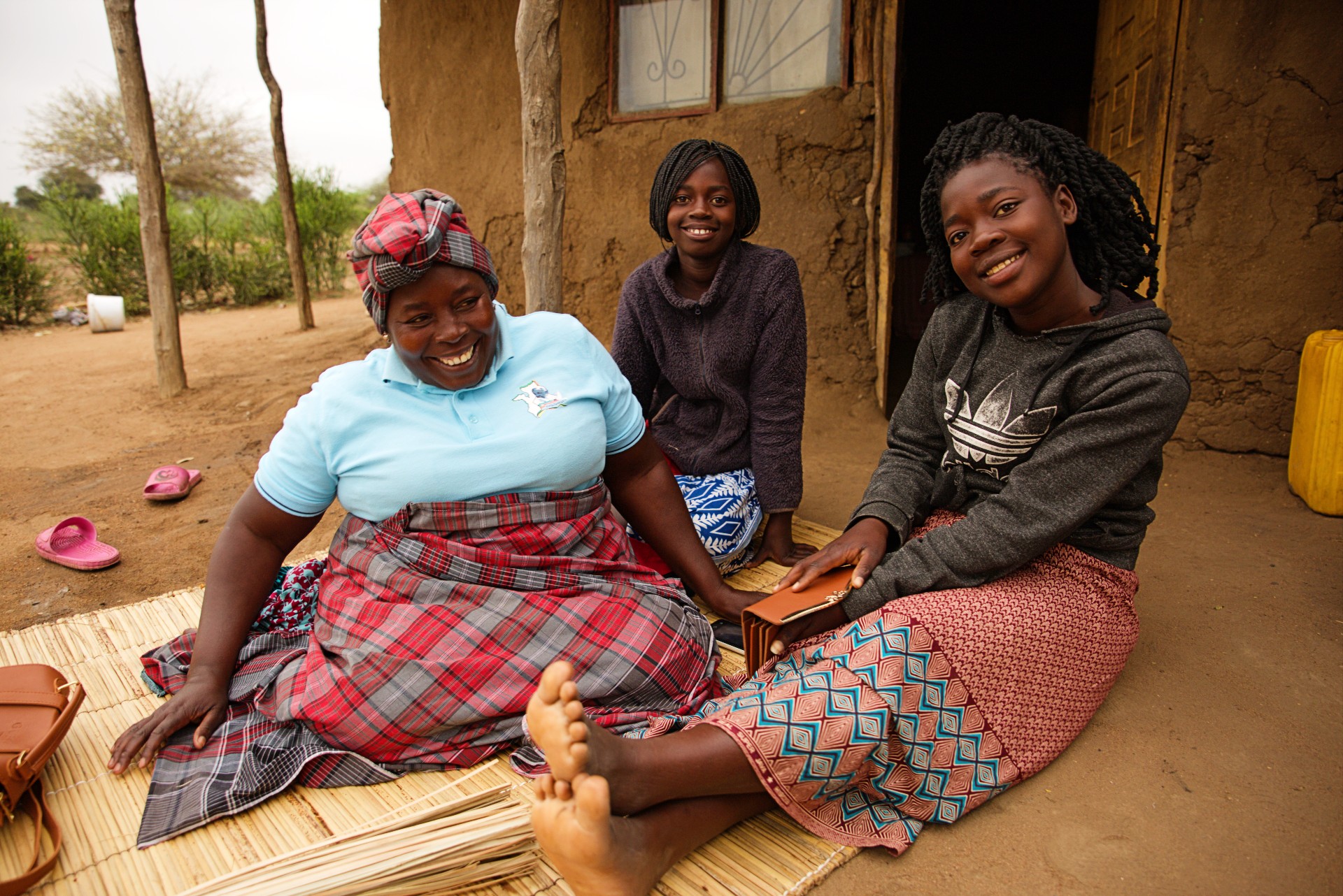 Linda Sarmento sits outside in front of her house with her two daughters.