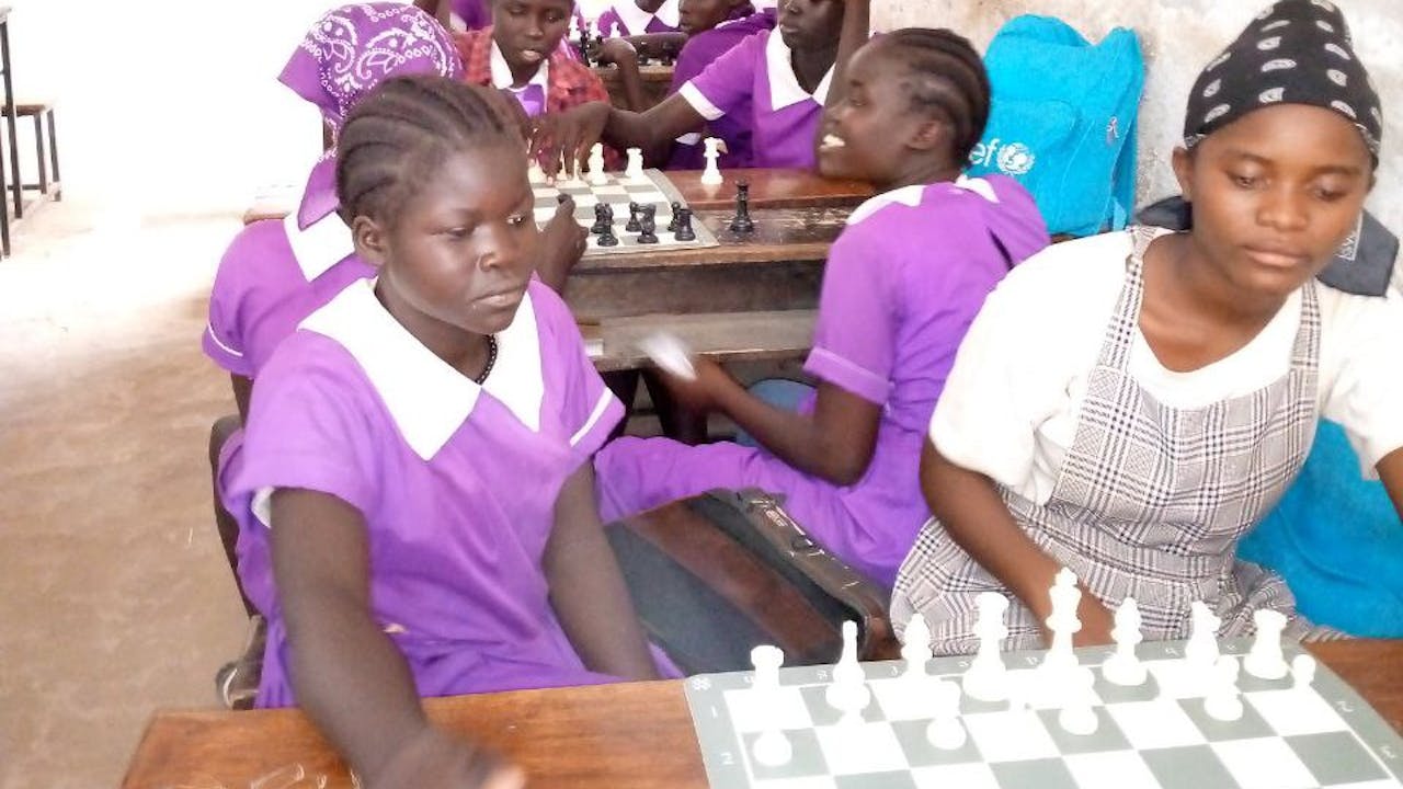 Girls in purple school uniforms play chess.