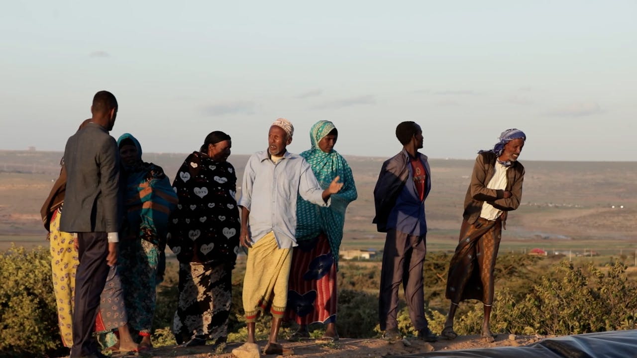 Miembros de la comunidad de Yasin parados en la orilla del embalse.