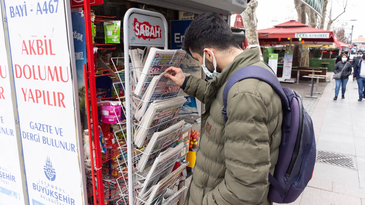 Morshed selects a Turkish newspaper from a newspaper stand.