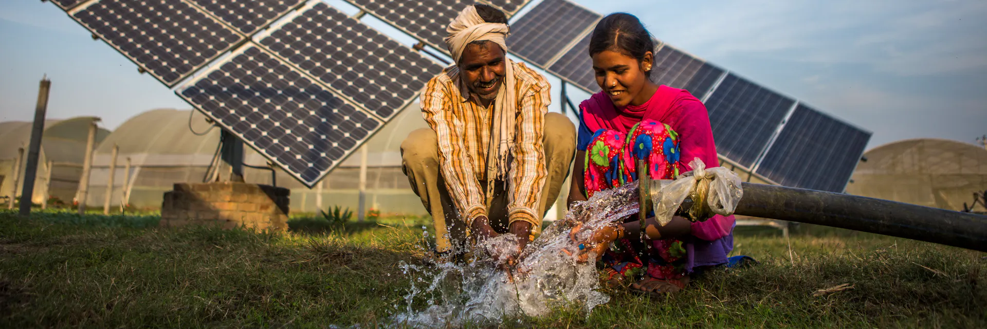 Le fermier et sa fille utilisent de l'eau pompée par une pompe à eau solaire.