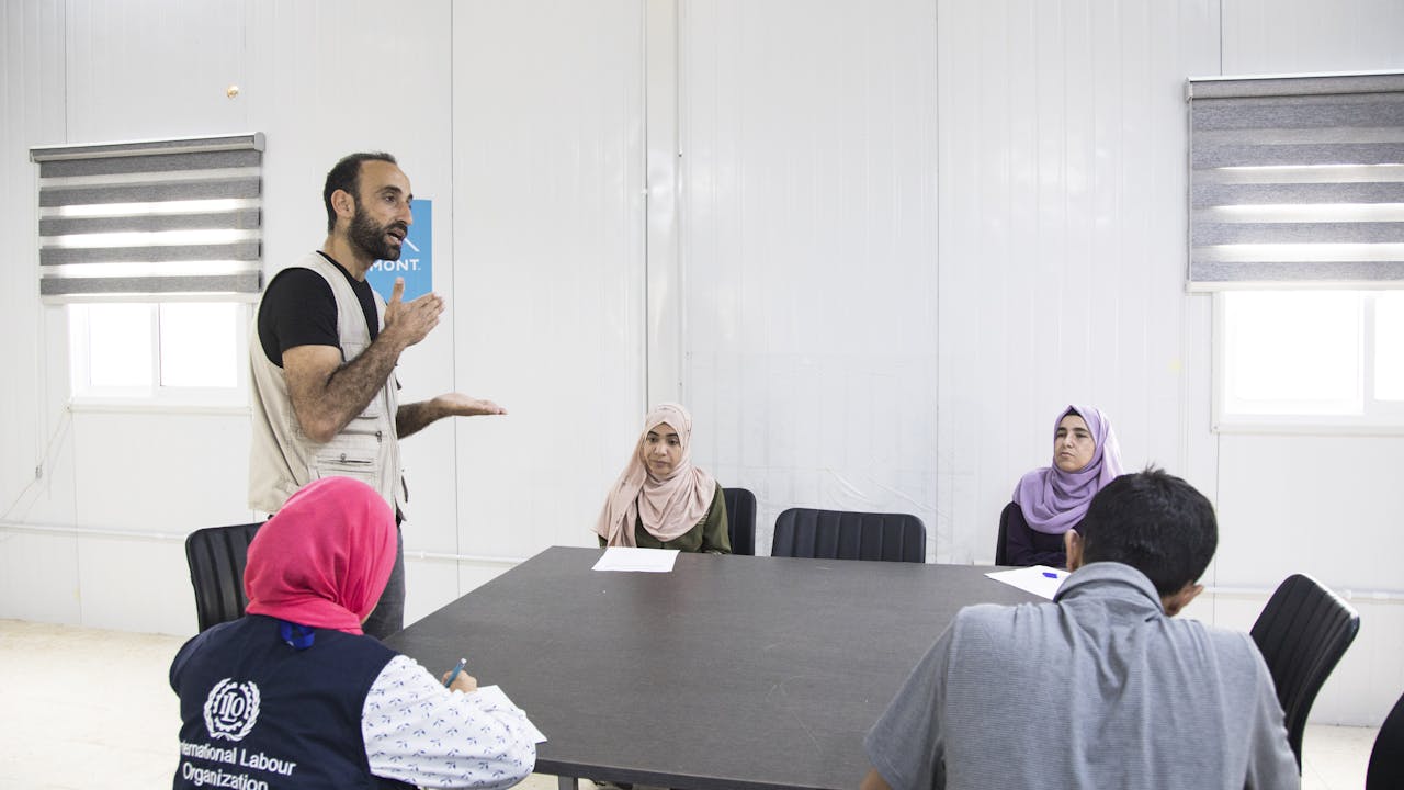 Abdel Halim al Qasir runs a career guidance session under the supervision of an ILO official for three fellow Syrian refugees on how to find jobs based on their skills in one of Jordan’s Za’atari refugee camp public spaces. 