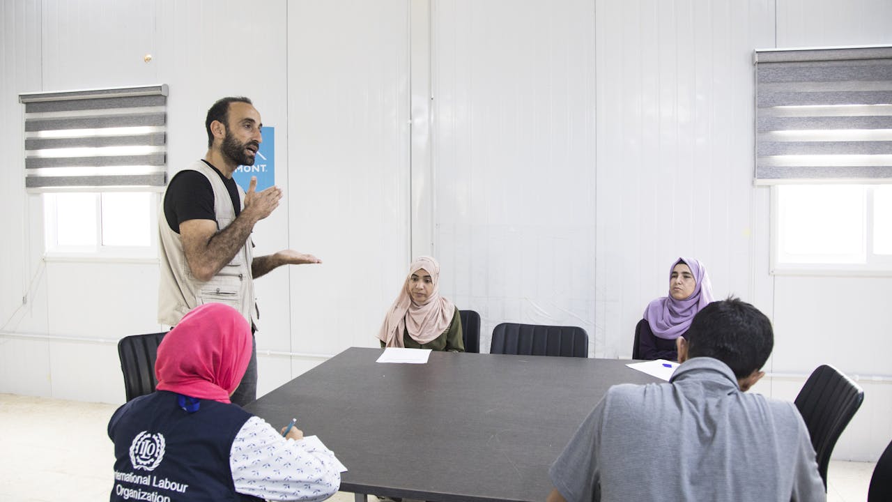 Abdel Halim al Qasir runs a career guidance session under the supervision of an ILO official for three fellow Syrian refugees on how to find jobs based on their skills in one of Jordan’s Za’atari refugee camp public spaces.