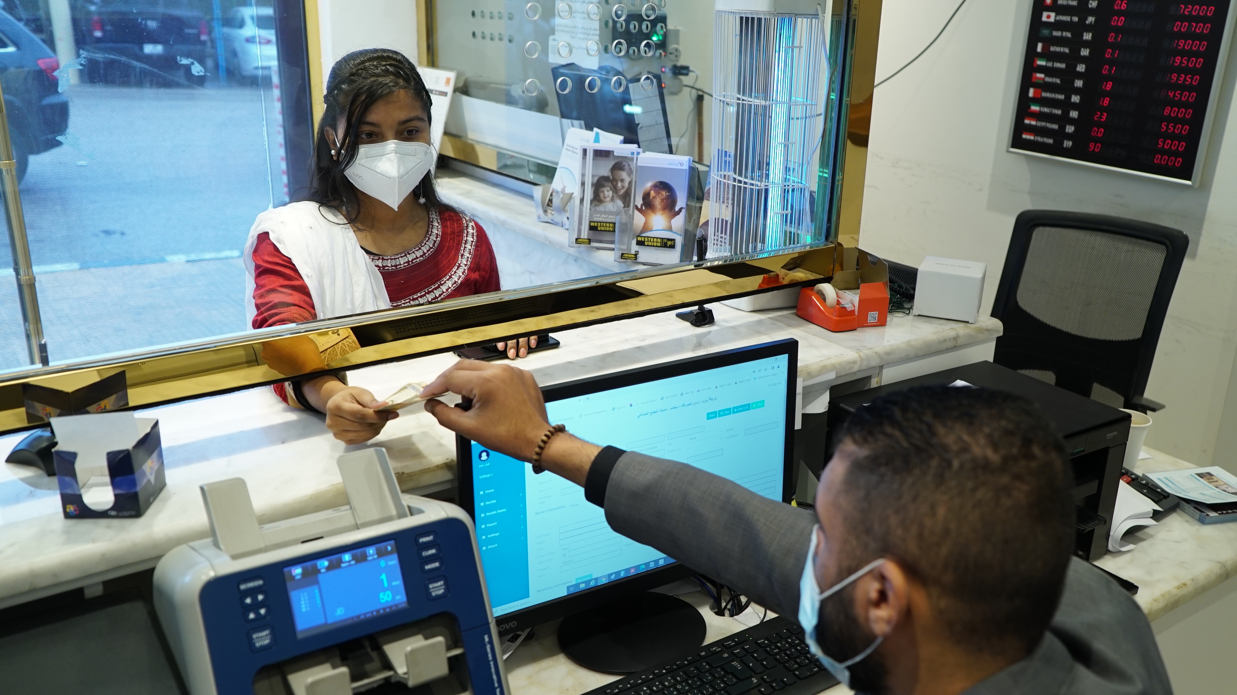 Maya Aktar hands money to a clerk at an international money transfer service.