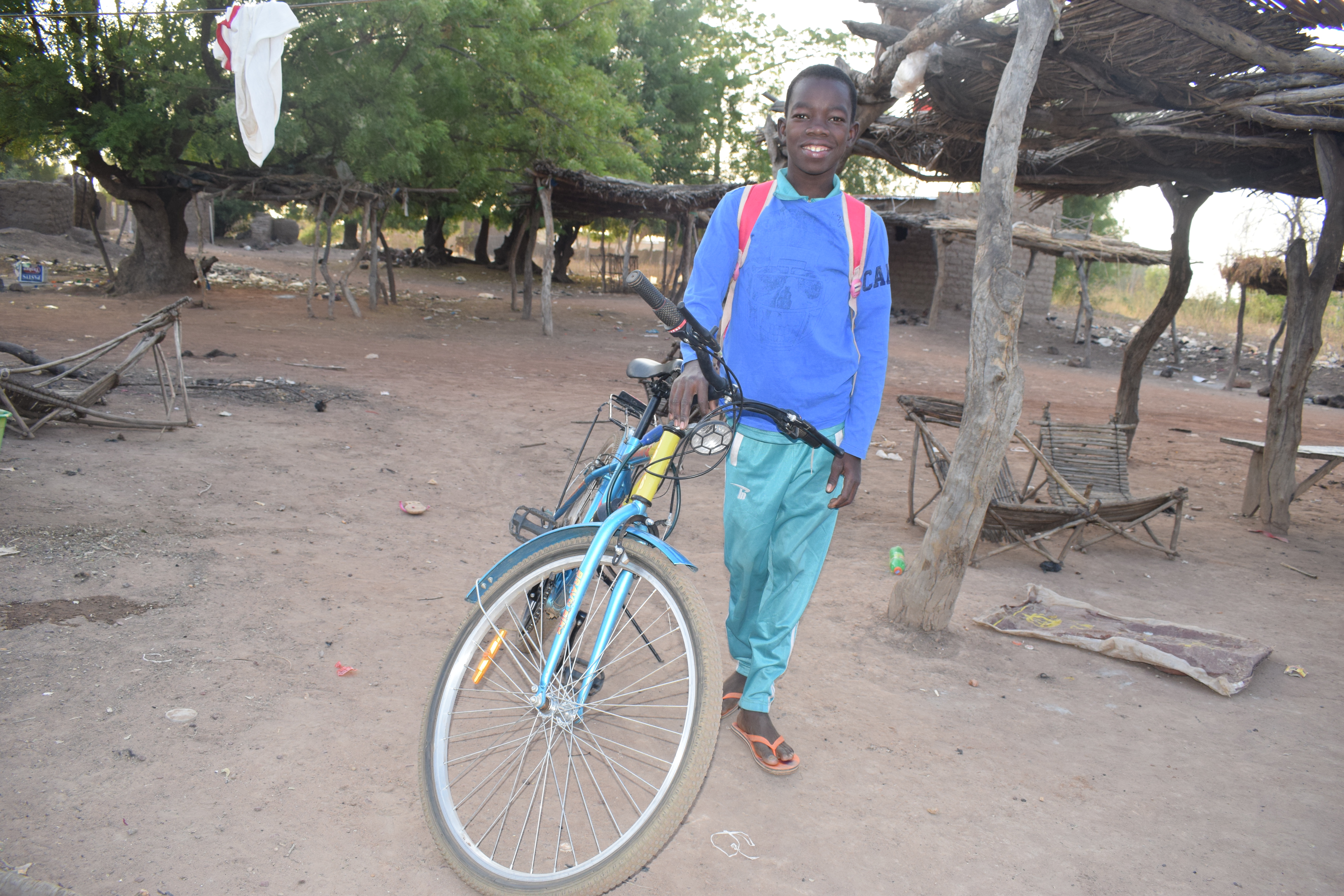 Domboué Nibéissé stands next to a bike and smiles.
