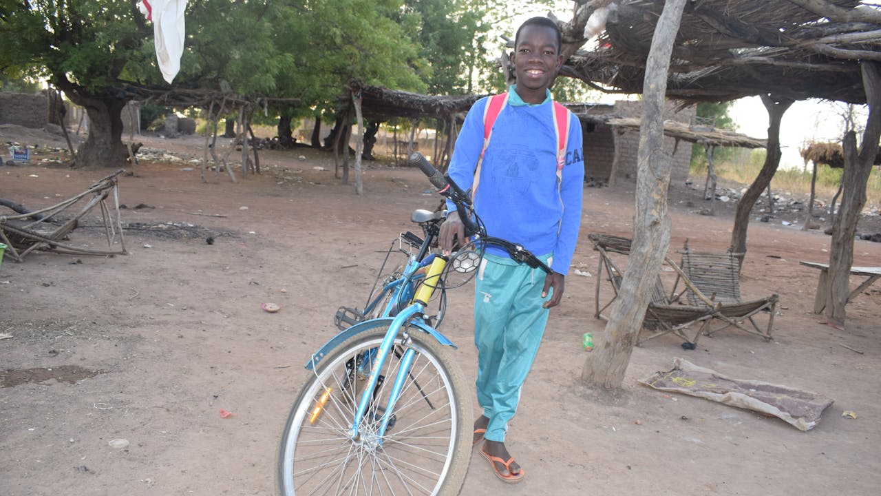 Domboué Nibéissé se tient à côté d'un vélo.