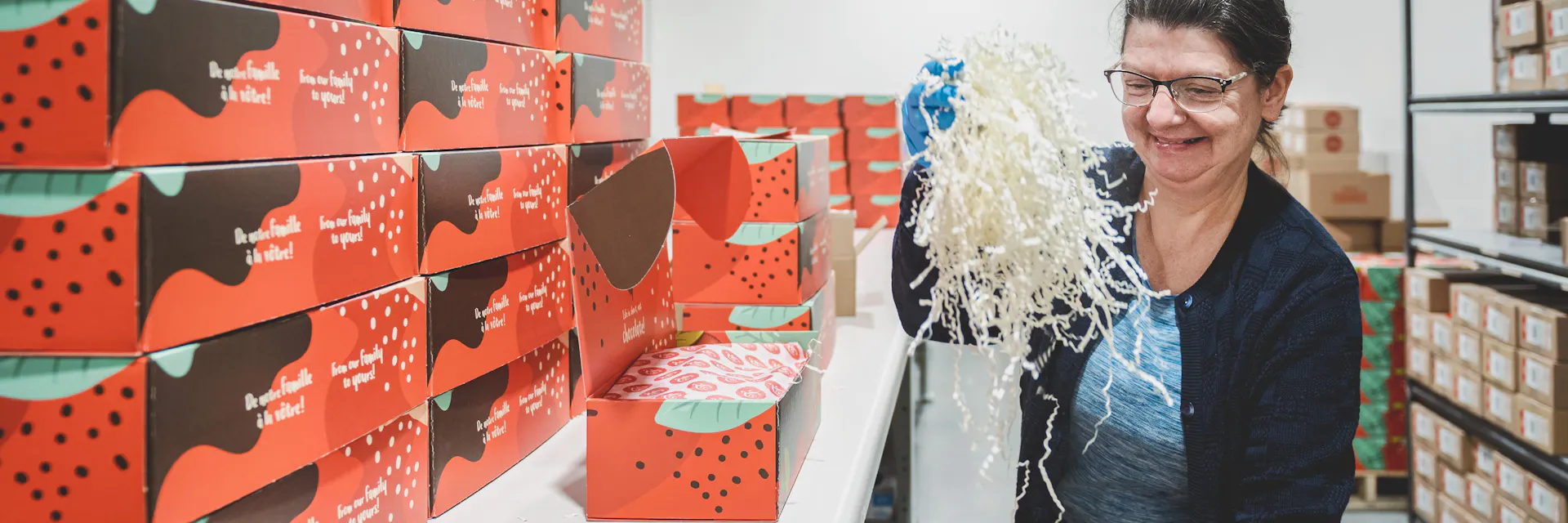 Une femme emballe des boîtes cadeaux.