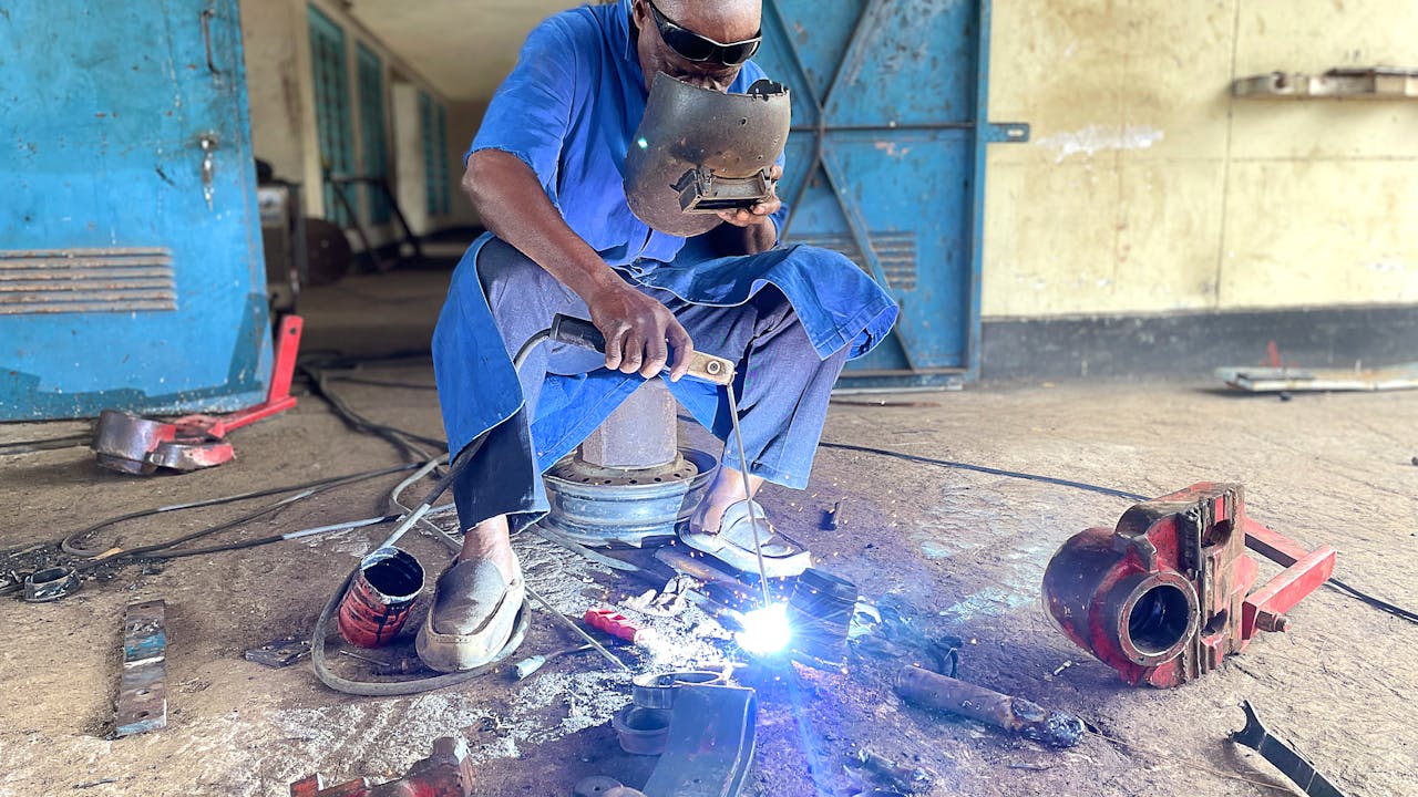 Sparks fly as Hussein Juma Hassan welds a metal part.