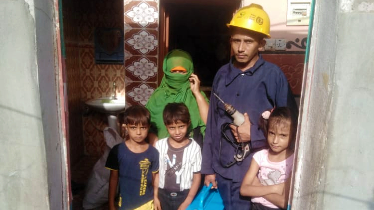 Muhammad Taher Muhammad al-Tahri stands in a doorway with his mother and three children, who are his young brothers and sister.  