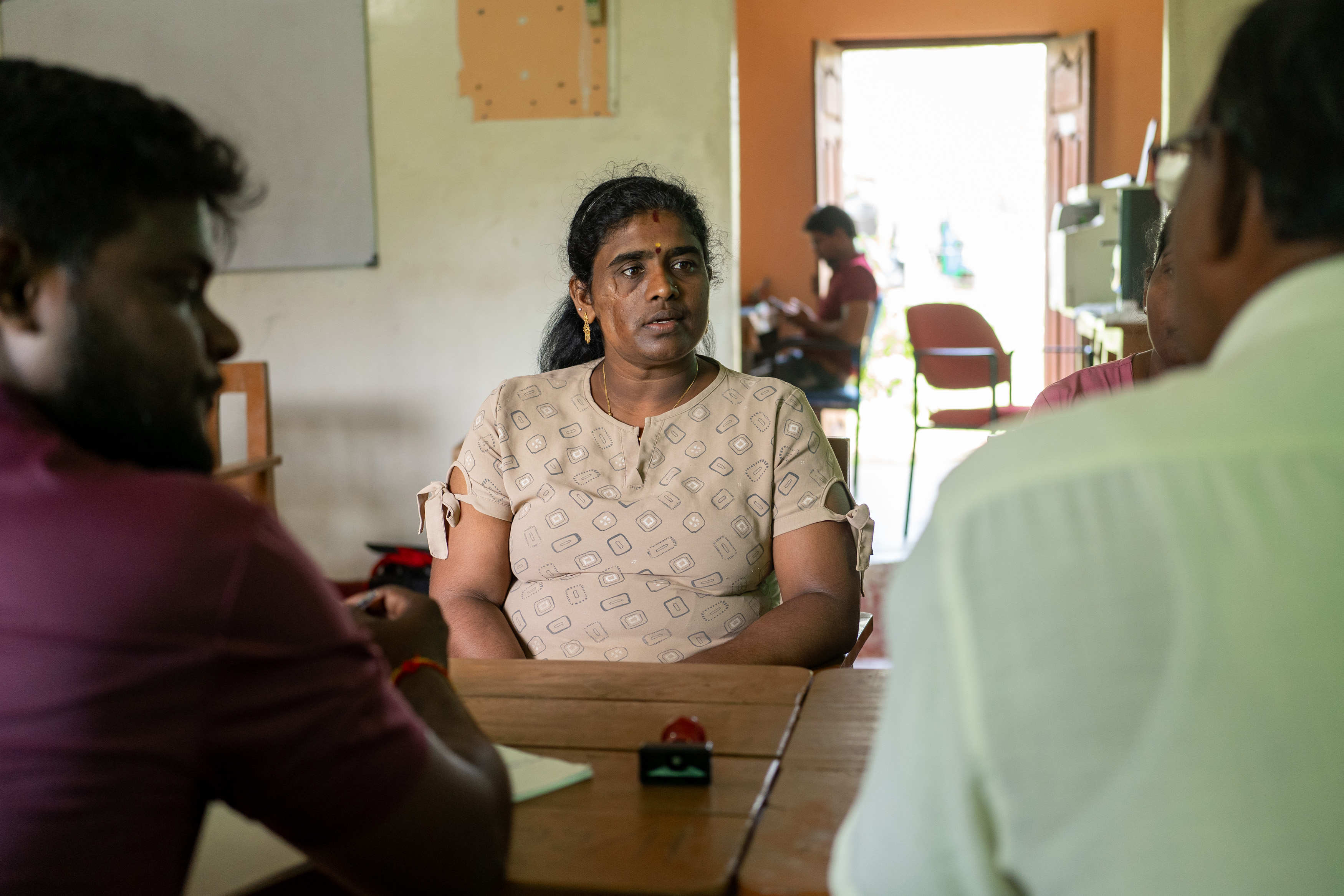 Leena Penildas Thatkuras sits at a table with other three-wheeler drivers who are part of her local cooperative.