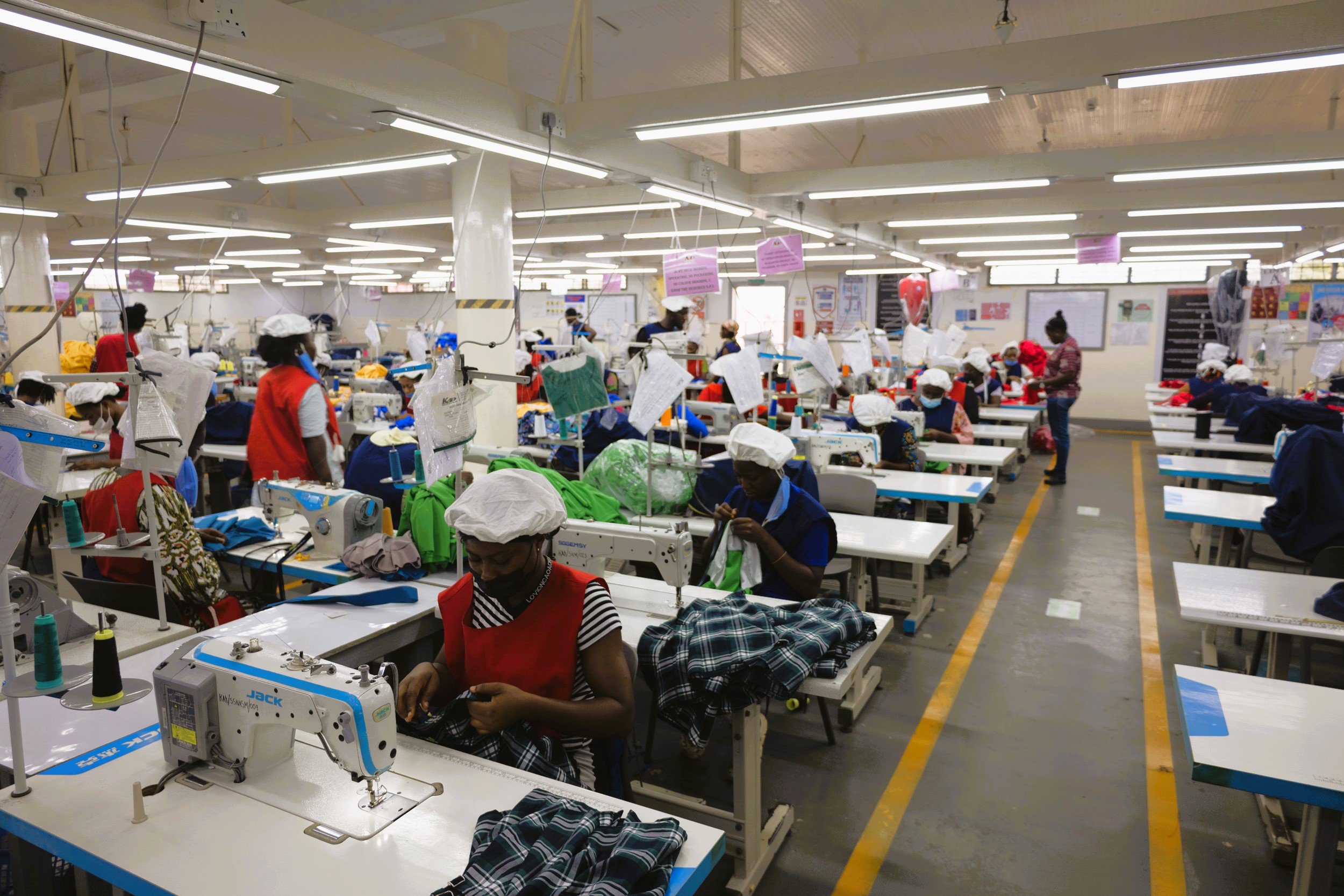 Wide shot of rows of women at work operating sewing machines at Linda Ampah’s garment factory. 