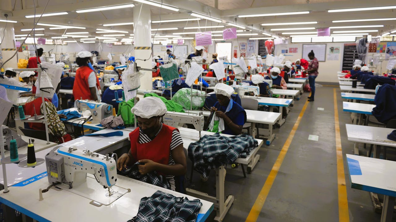 Wide shot of rows of women at work operating sewing machines at Linda Ampah’s garment factory.