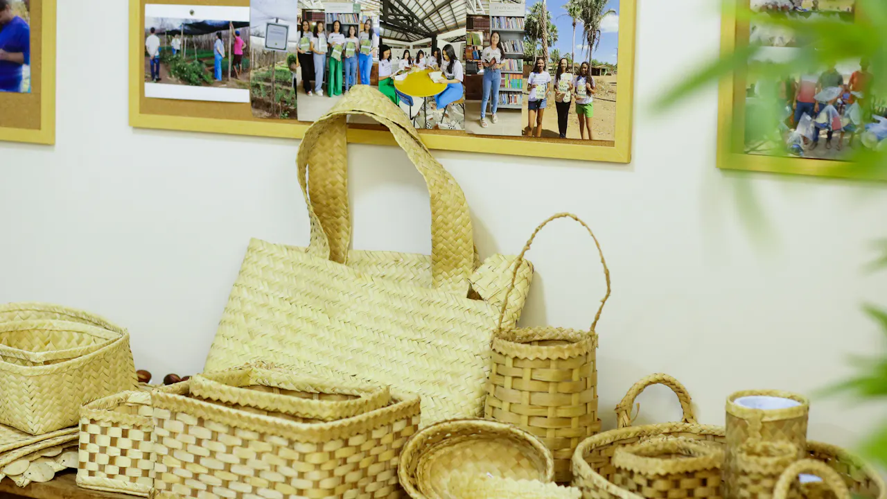 Baskets, bags, and containers woven from carnauba are displayed on a table. On the wall above the table, photos show the groups of artisans who produced the handicrafts.