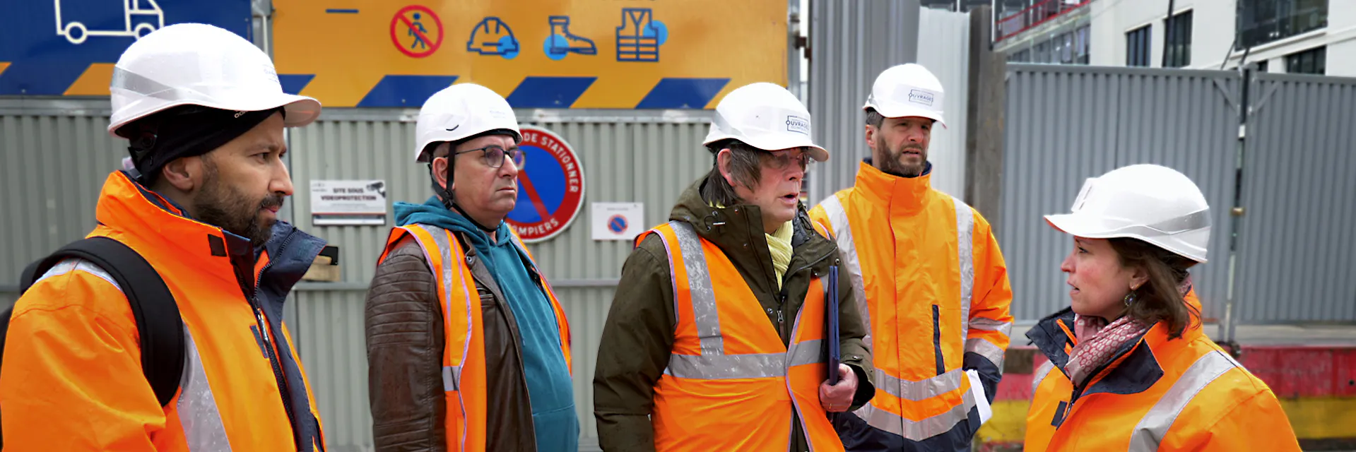 Des ouvriers sur les chantiers des Jeux et des représentants des syndicats français appliquant la Charte sociale sur le terrain (au premier rang desquels Bernard Thibault, ancien membre de l'OIT). Sur la photo, ils discutent entre eux, vêtus de gilets orange et de casques blancs. Oct 2023