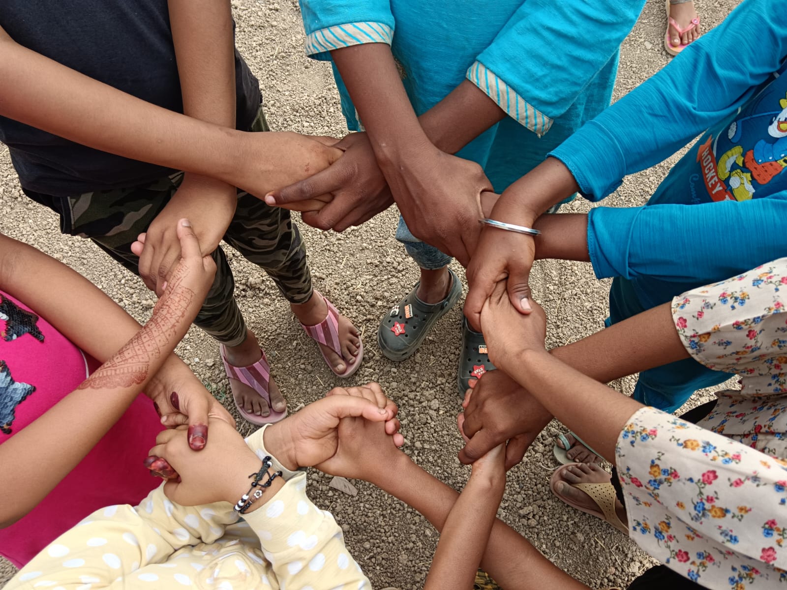 Photo montrant sept paires de mains de jeunes gens se tenant l’une l’autre pour former un cercle. Photo fournie par le GSNP+. (2024)